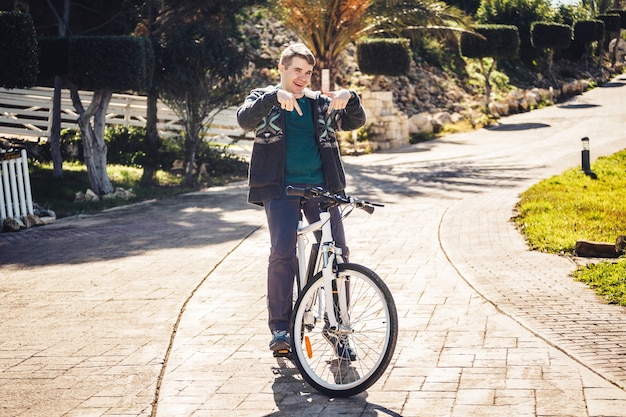 Young man riding bike in park showing thumb up.