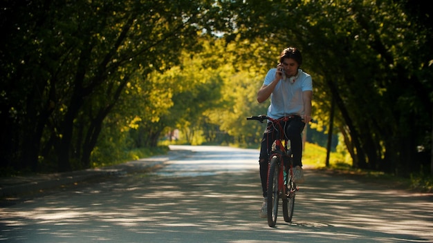 自転車に乗って彼の電話で話している若い男