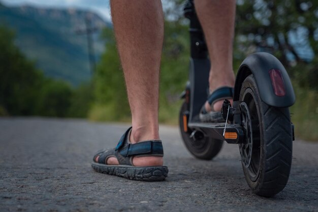 Young man riding an electric scooter on mountain range Ecological transportation concept