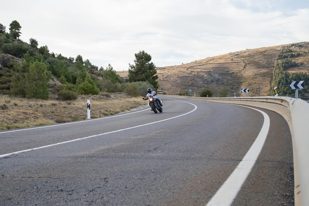 Young man riding motorcycle on road against cloudy sky