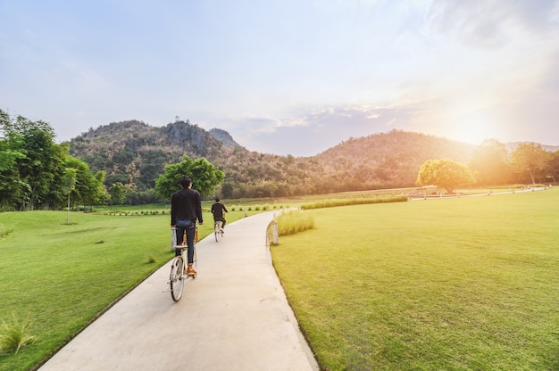 Young man riding retro bicycle in public park with sunlight