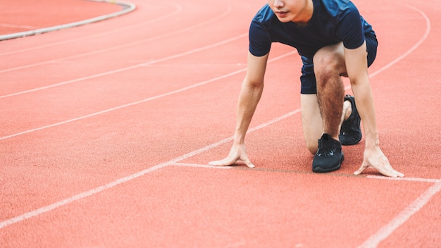 写真 レーストラックのスタートポイントで若い男のランナー