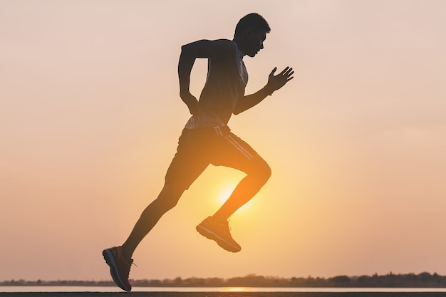 Young man runner running on running road in city park