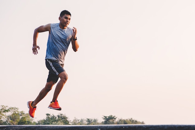 Young man runner running on running road in city park