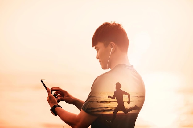 Photo young man running on beach and checking heart rate monitor on smart phone concept