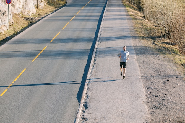 Young man running outside along an empty mountain road