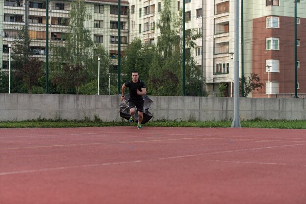 Young Man Running With Parachute On Sports Field