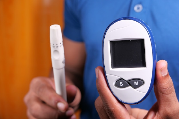 Young man's hand measure glucose level at home.