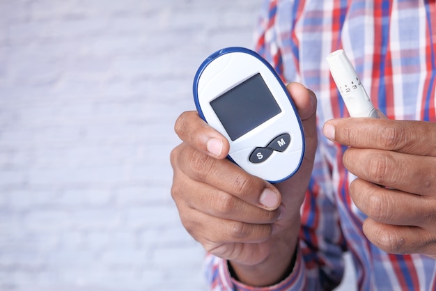 Young man's hand measure glucose level at home.