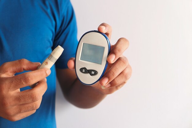 Young man's hand measure glucose level at home.