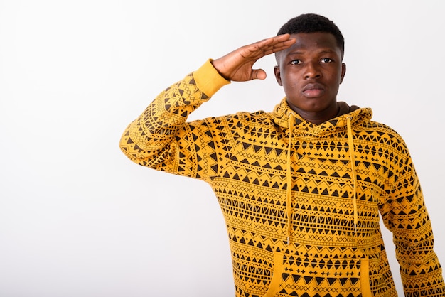 Young man saluting against white wall