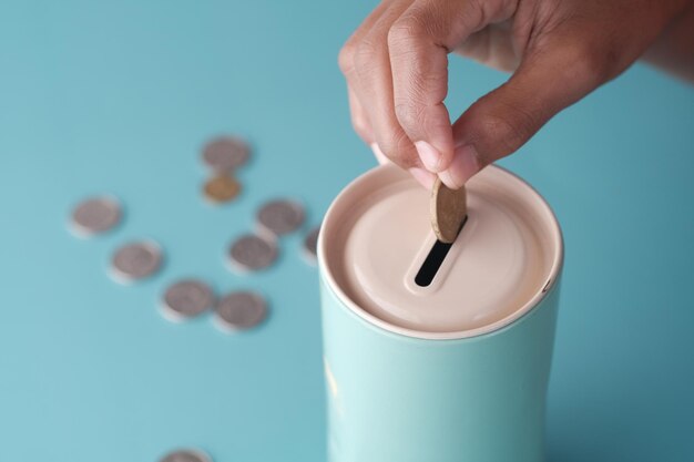 Young man saving coins in a jar white sited