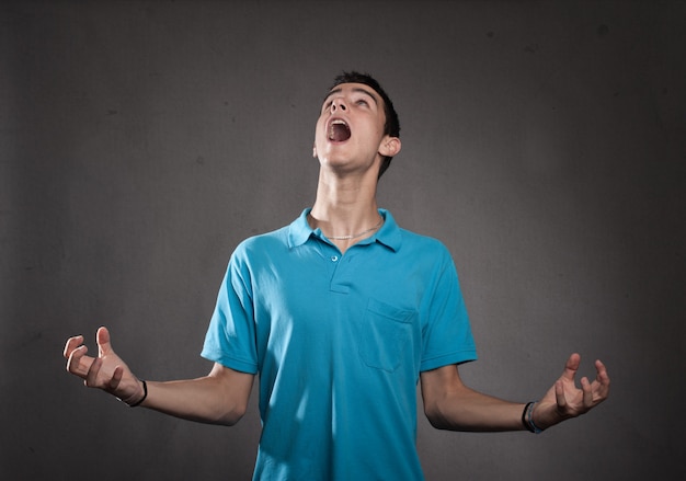 Young man screaming on a grey background