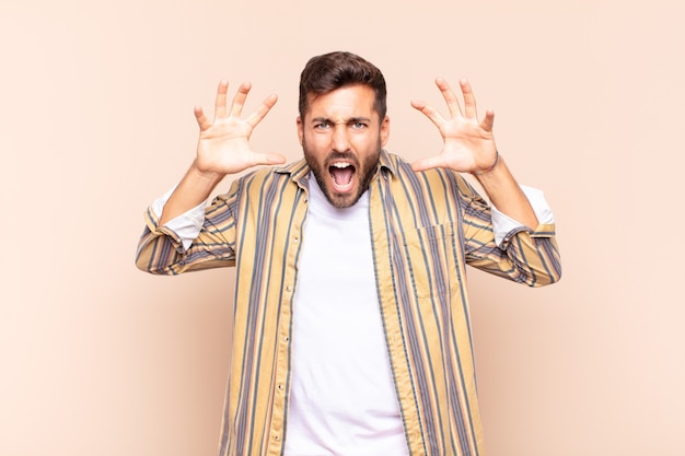 Young man screaming in panic or anger, shocked, terrified or furious, with hands next to head