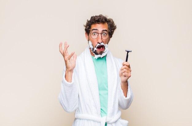 Young man screaming with hands up in the air, feeling furious, frustrated, stressed and upset