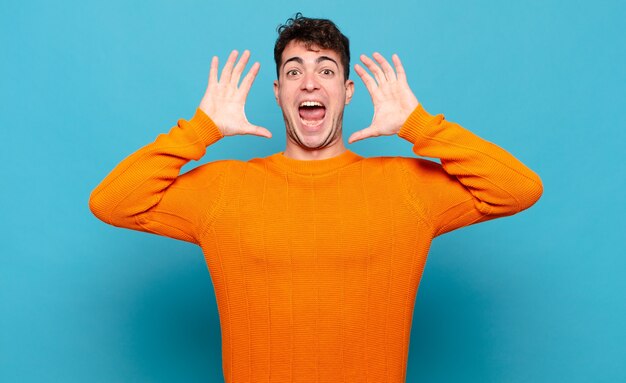 Young man screaming with hands up in the air, feeling furious, frustrated, stressed and upset