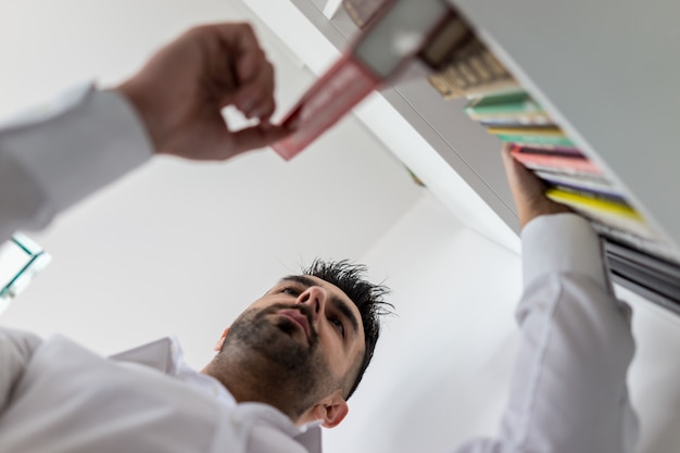 Young man searching for the right book at library shelf