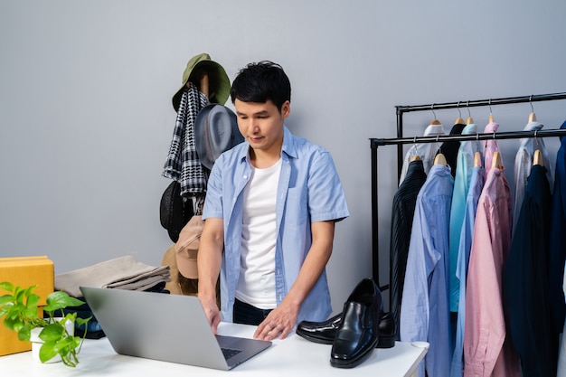 Young man selling clothes and accessories online by laptop computer live streaming. Business online e-commerce at home