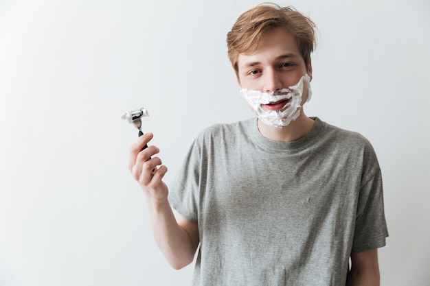 Young man in  shaving foam holding razor