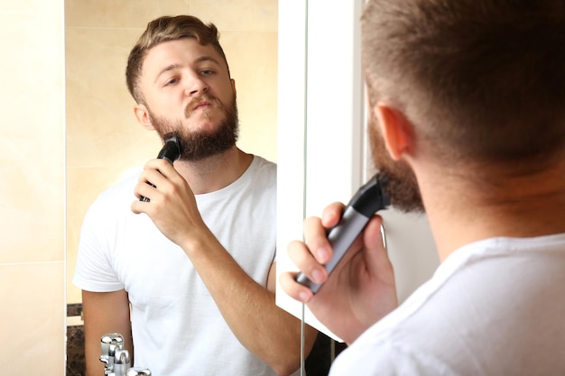 Young man shaving his beard in bathroom