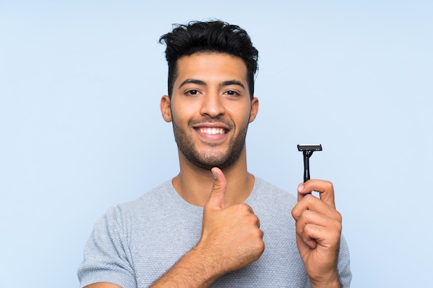 Giovane che si rade la barba con il pollice in su perché è successo qualcosa di buono