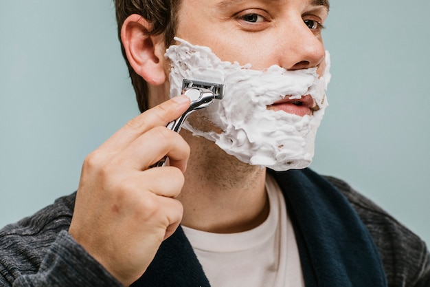 Young man shaving his beard