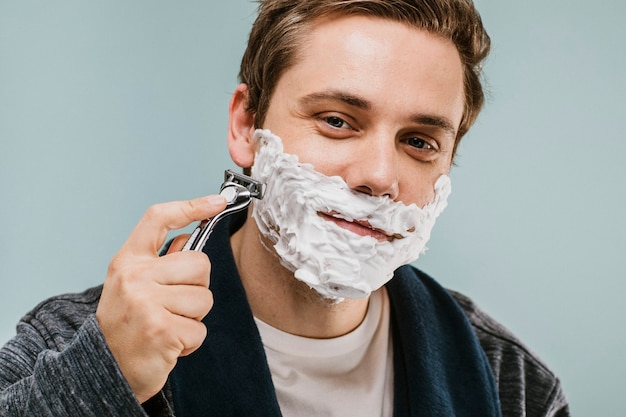 그의 수염을 면도하는 젊은 남자