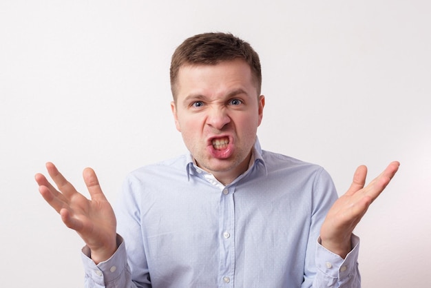 Young man in shirt in anger shouts and threatens