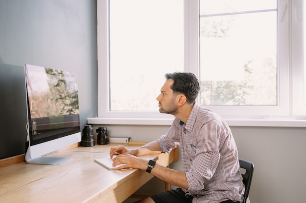 Young man in a shirt working on a computer at home