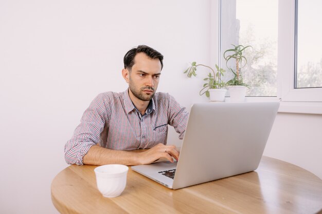 Young man in a shirt working on a laptop at home