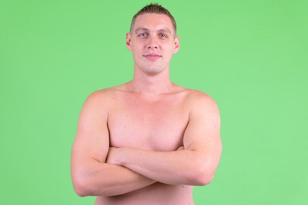  young man shirtless against green wall