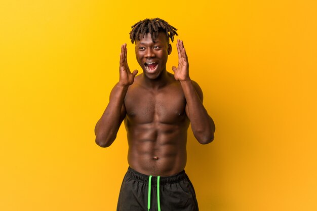 Young man shirtless wearing swimsuit and laughing