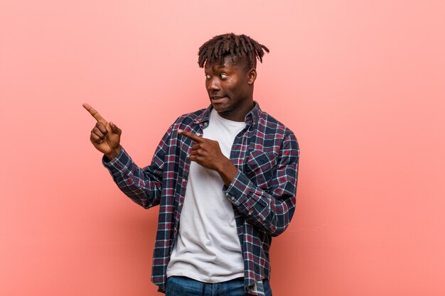 Young man shocked pointing with index fingers to a copy space.