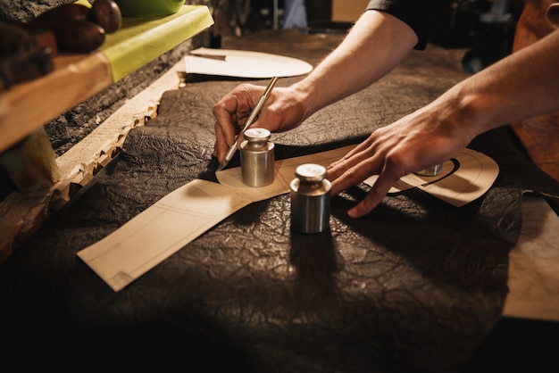 Young man shoemaker at footwear workshop.