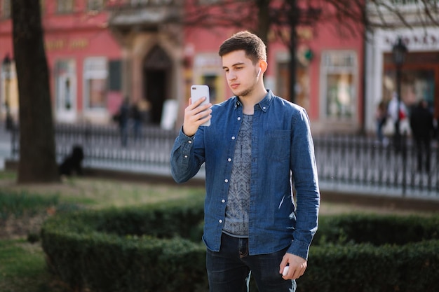 Young man shoots video on smartphome in centre of the city