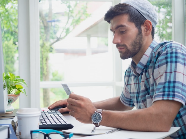 Giovane che compera online con la carta di credito a casa