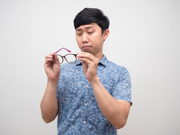 Young man shortsighted take off his glasses try to look isolated