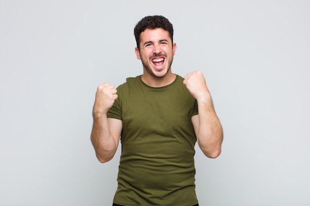 Young man shouting triumphantly, laughing and feeling happy and excited while celebrating success