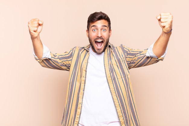 Young man shouting triumphantly, looking like excited, happy and surprised winner, celebrating