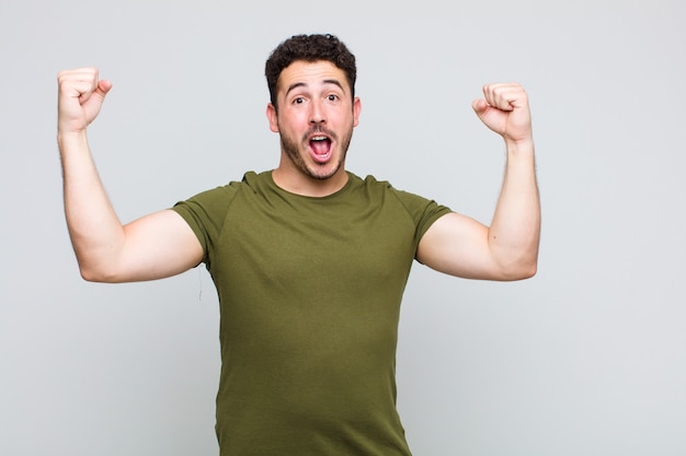 Young man shouting triumphantly, looking like excited, happy and surprised winner, celebrating