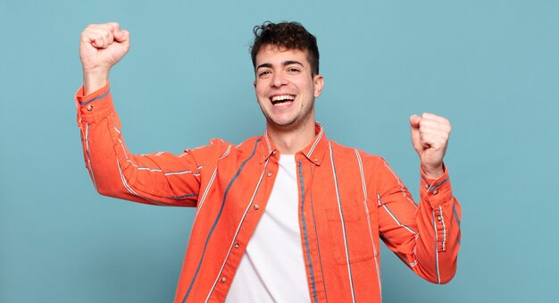 Young man shouting triumphantly, looking like excited, happy and surprised winner, celebrating