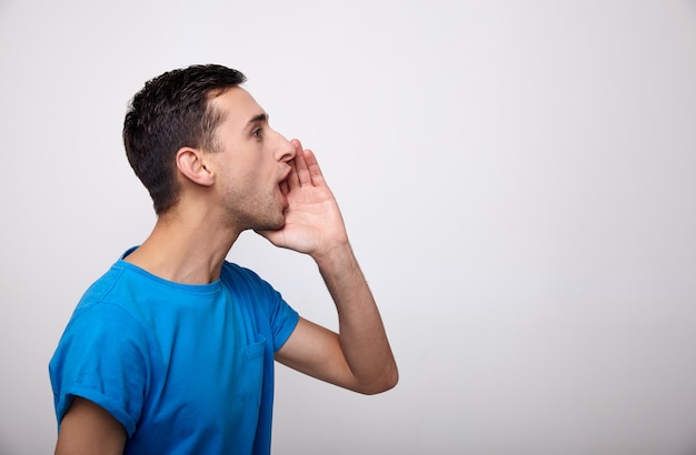 A young man shouts standing against a white.