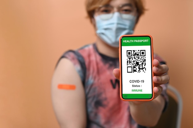 Giovane che mostra passaporto sanitario su smart phone vaccinazione e immunizzazione