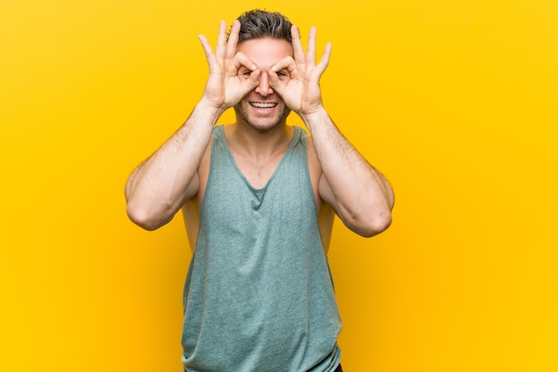 Young man showing okay sign over eyes
