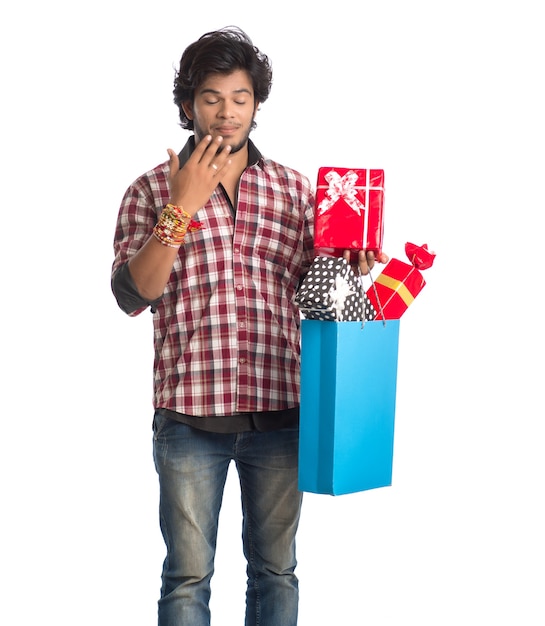 Young man showing rakhi on his hand with shopping bags and gift box on the occasion of Raksha Bandhan festival.