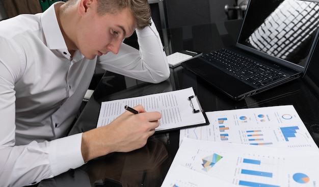 Young man signs insurance in bright office