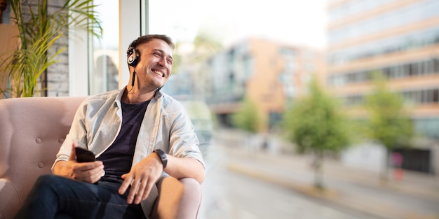 Young man sit and speak with hands-free and smile