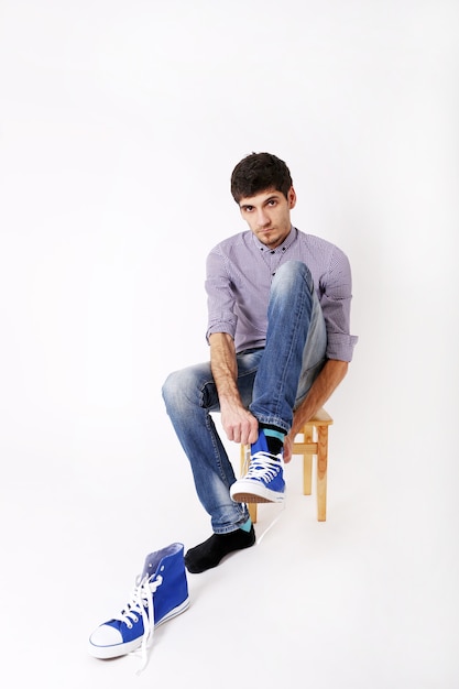 Young man sit and wear sneakers