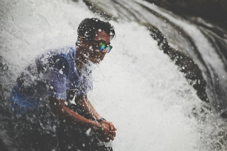 Photo young man sitting amidst flowing water