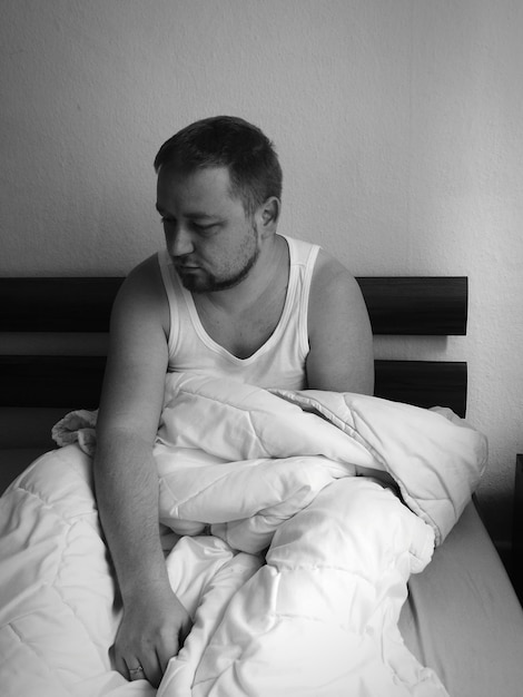 Young man sitting on bed at home